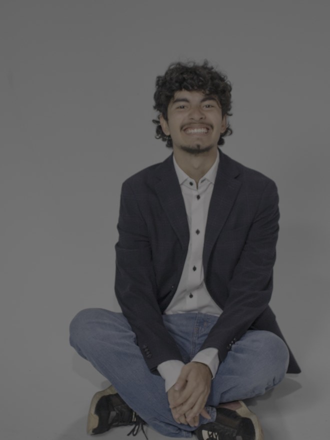 Tony sitting cross-legged on the floor in a blazer, smiling broadly