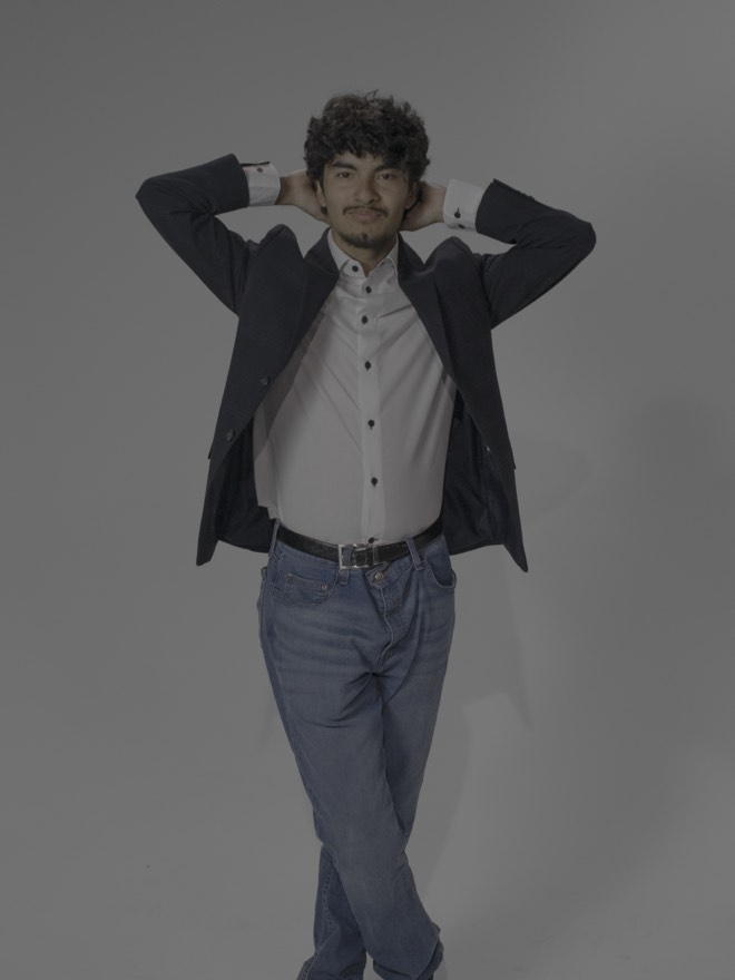 Tony standing with his hands behind his head, blazer open over a white shirt