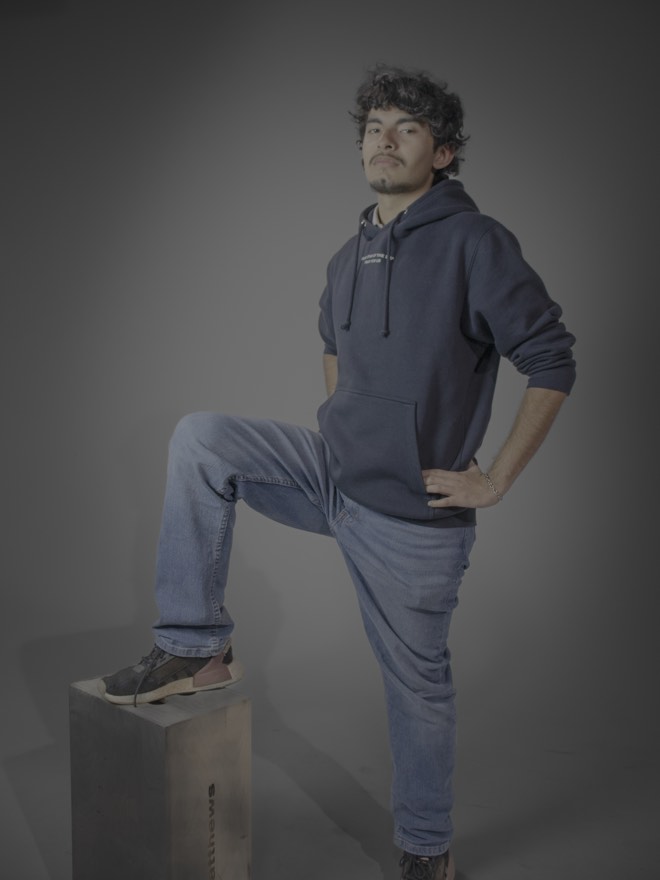Tony standing with one foot up on a box, hand on hip, in a hoodie and jeans